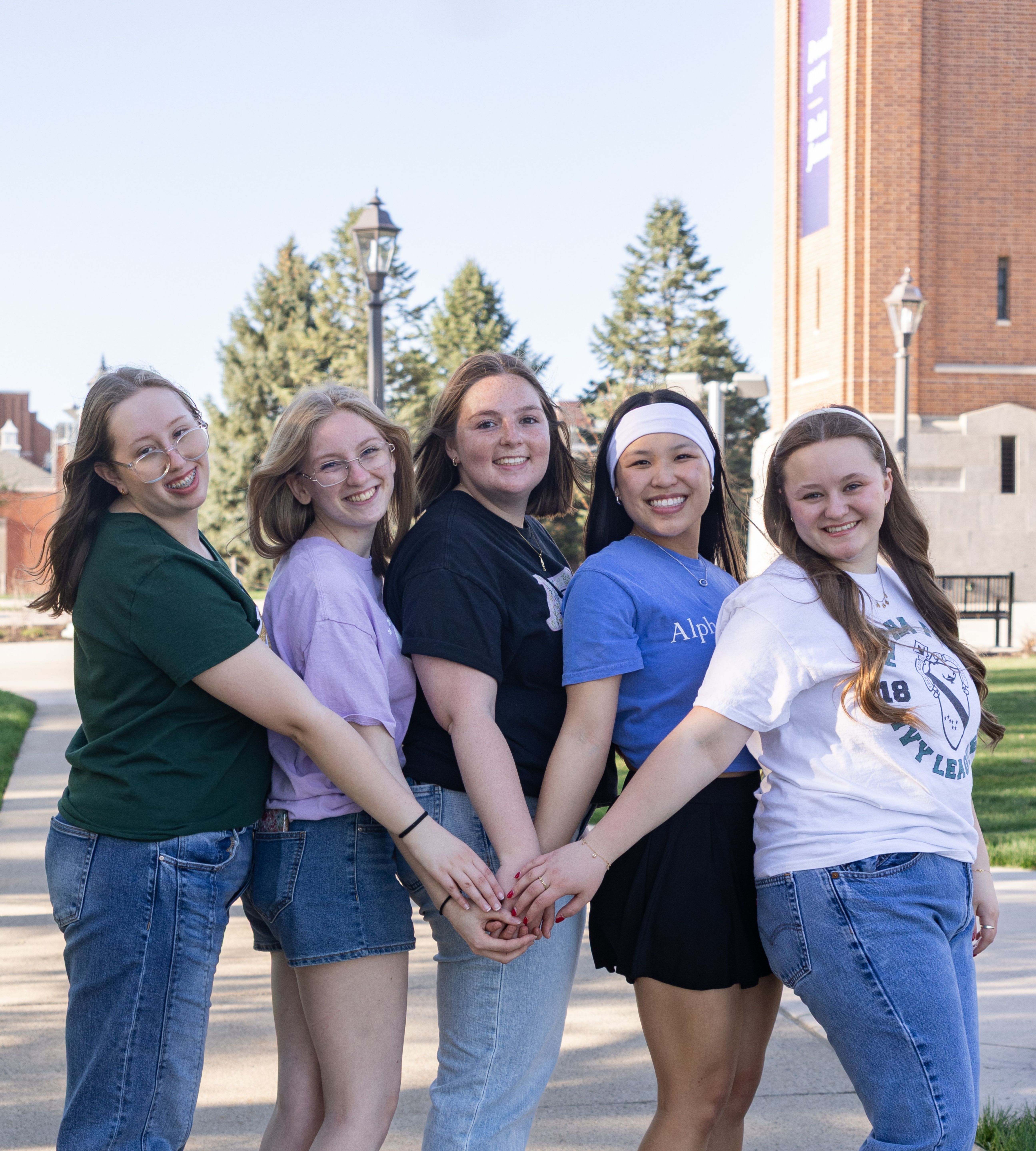 Five women posing in front of campanile
