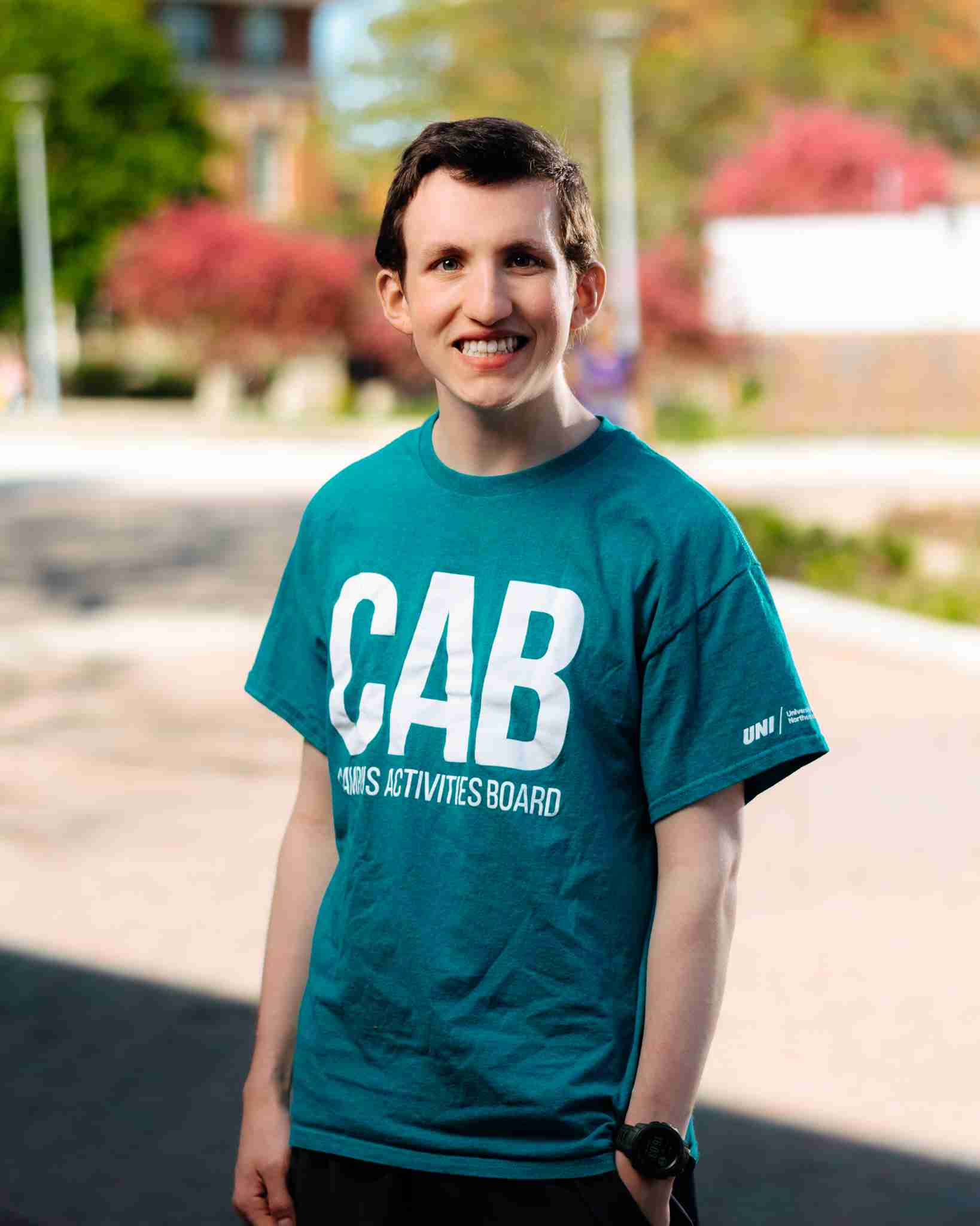 Guy with brown hair standing outside wearing teal shirt