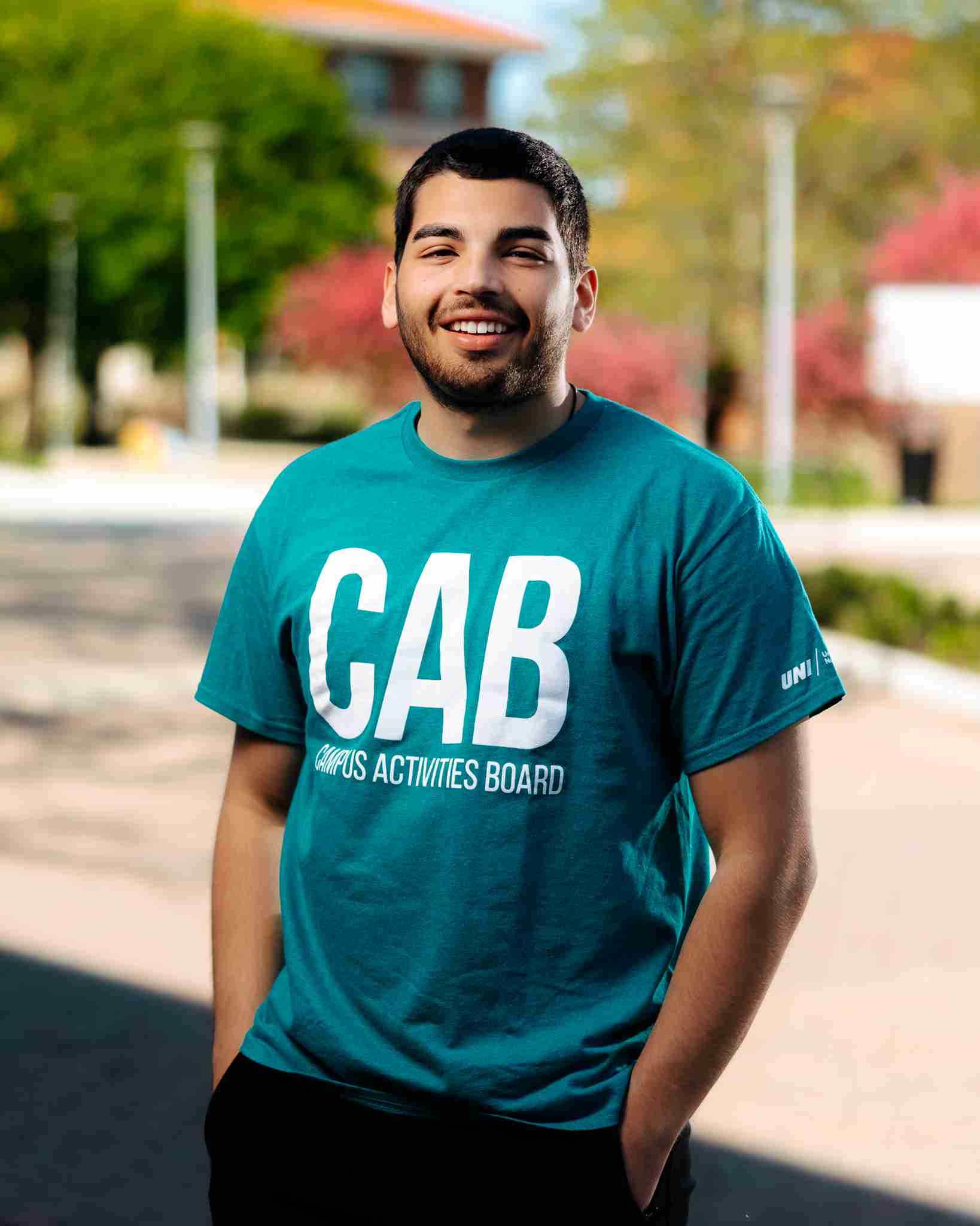 Guy with brown hair standing outside wearing teal shirt