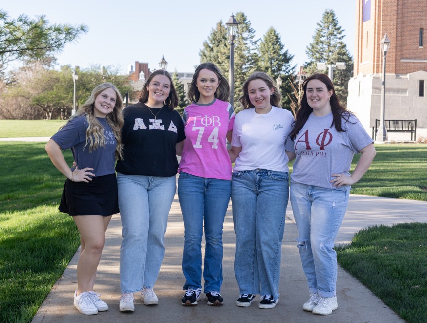Five women posing in front of campanile