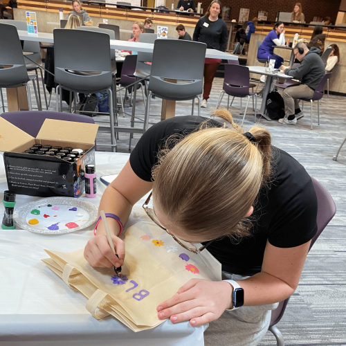 Student painting a tote bag in Maucker Union